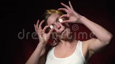 一个<strong>活泼开朗</strong>的金发女人在用棉花糖代替眼睛，然后吃它们时做鬼脸